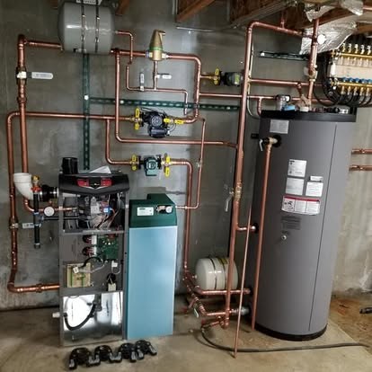 Boiler with circulator pumps, expansion tank and a tall indirect water heater tank in a basement mechanical room