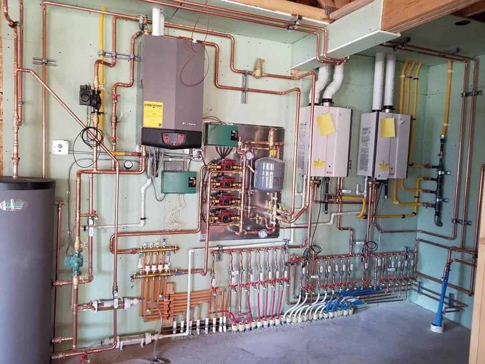 Hydronic heating mechanical room with a wall-mounted boiler, two tankless water heaters, radiant heat manifolds and copper piping